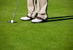Close-up of man putting golf ball in to hole